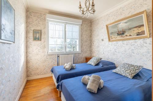 two beds in a room with blue sheets at Ty Ar Bleiz Gwenn - La maison du Loup Blanc in Trégarvan