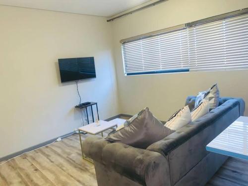 uma sala de estar com um sofá e uma televisão em DMN City Merensky Apartment em Windhoek