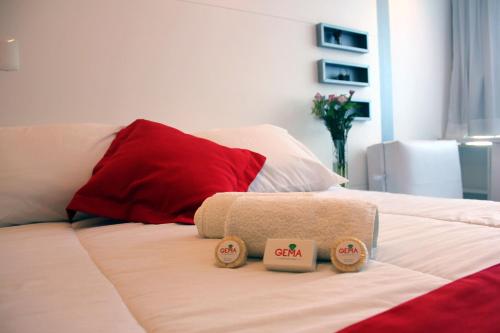 Cama blanca con 2 almohadas y almohada roja en Hotel Gema Luxury Suites, en Montevideo