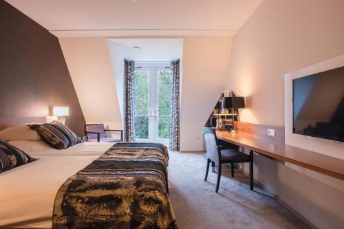 Habitación de hotel con cama, escritorio y TV. en Hotel Woudschoten, en Zeist