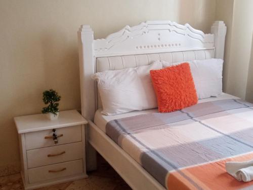 a bedroom with a white bed and a night stand at MT. KENYA PALACE in Nyeri