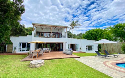 a large white house with a deck and a pool at Woodlands Beach Villa in Southbroom