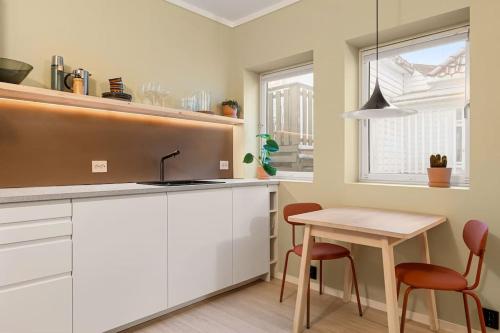 a kitchen with white cabinets and a table and chairs at Fresh studio apartment, a short walk from Bryggen in Bergen
