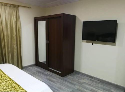 1 dormitorio con TV de pantalla plana y armario en بوابة الريادة, en Ar Riḩāb