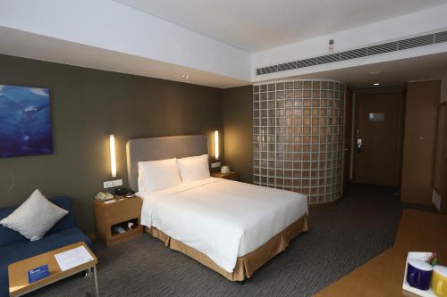 1 dormitorio con 1 cama grande y 1 sofá azul en Holiday Inn Express Shanghai Jinsha, an IHG Hotel en Shanghái