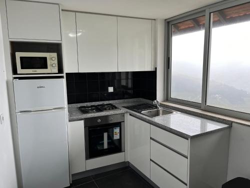 a kitchen with white cabinets and a sink and a microwave at Casa da Oliveira in Mesão Frio