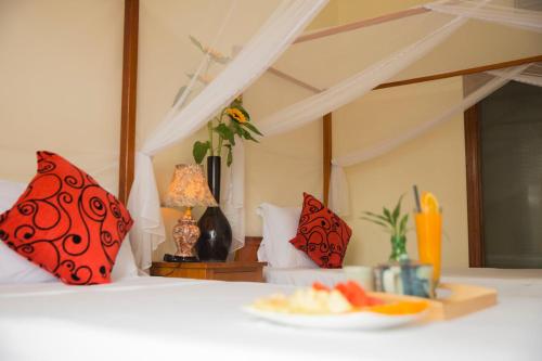 a bed with red pillows and a plate of fruit on it at Phong Nha Lake House Resort in Phong Nha