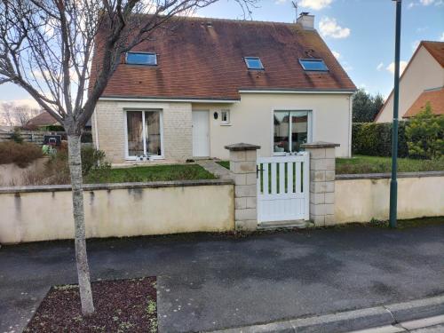 una casa blanca con una puerta blanca y un árbol en Sous le pommier, en Douvres-la-Délivrande