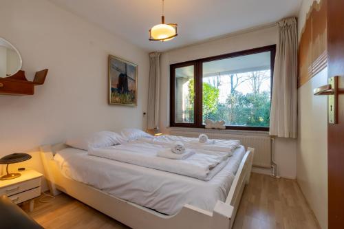 a bedroom with a large white bed with a window at Appartement - Kievitenlaan 1 - Veere 'Nescio' in Veere