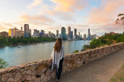 a woman standing next to a stone wall overlooking a river at Comfy Character QLD’r ~ 3Bed Self-Contained-Upstairs House w/Parking ~ Woolloongabba in Brisbane