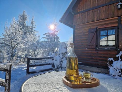 a bottle on a table in front of a cabin at Brvnare Na Brdu in Šljivovica