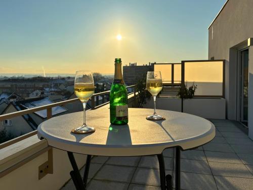 uma mesa com dois copos e uma garrafa de vinho em Peri - Lit Kingsize - Terrasse vue Tour Eiffel #SirDest em Bezons