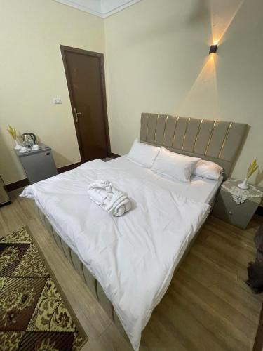 Una cama con sábanas blancas y una bata. en نزله البطران en El Cairo