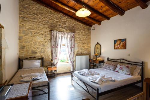 a bedroom with two beds and a stone wall at Allaria villa in Margarítai