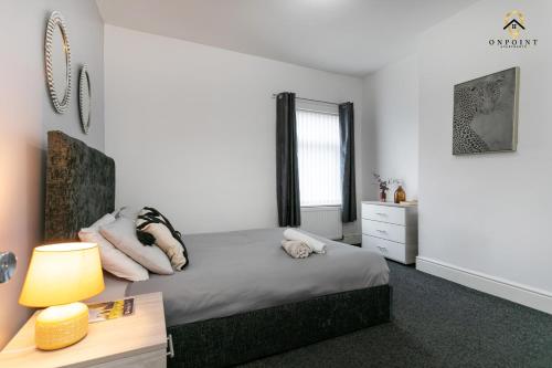een slaapkamer met een bed en een bureau met een lamp bij OnPoint - Spacious 4 Bed House in Hanley