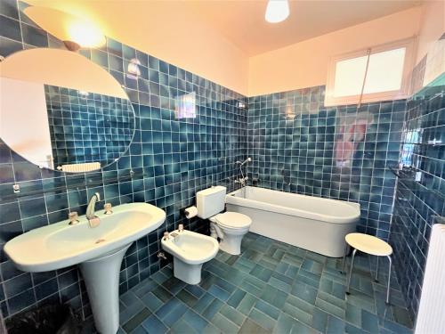 La salle de bains est pourvue de carrelage bleu, d'un lavabo et de toilettes. dans l'établissement Appartement vue mer Carmino Ajaccio, à Ajaccio
