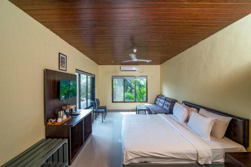 um quarto com uma cama grande e um sofá em Silvanus Forest Retreat, Alibaug em Alibag