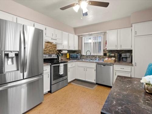 a kitchen with white cabinets and stainless steel appliances at Lovely 3-bedroom rental unit with free parking! in Anchorage