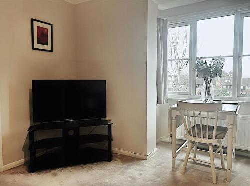 ein Wohnzimmer mit einem TV und einem Tisch mit einem Stuhl in der Unterkunft Apartment in Epsom With Free Parking in Epsom