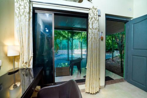 a room with a glass door with a view of a house at Silvanus Forest Retreat, Alibaug in Alibaug