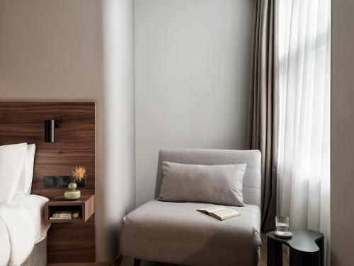 a bedroom with a bed and a chair with a book at The Newel Acropolis in Athens