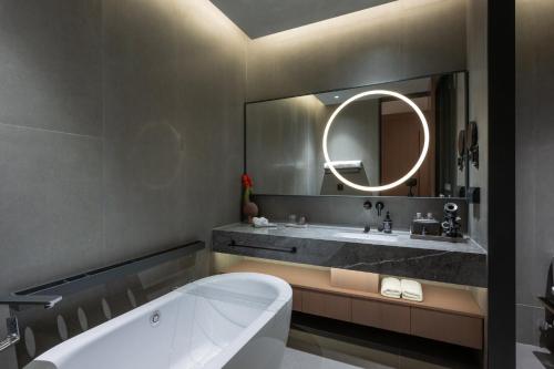 a bathroom with a tub and a sink and a mirror at Jiangnan House Guanqianjie in Suzhou