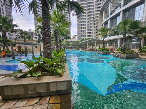 a large swimming pool with palm trees and buildings at 3BR Flat in Taman Anggrek Residence in Jakarta