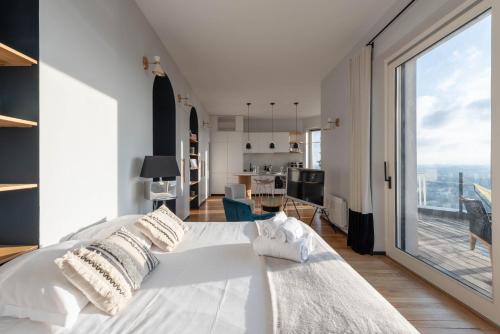 1 dormitorio con cama blanca y ventana grande en Le 360 - Appt vue panoramique sur Lyon, en Sainte-Foy-lès-Lyon