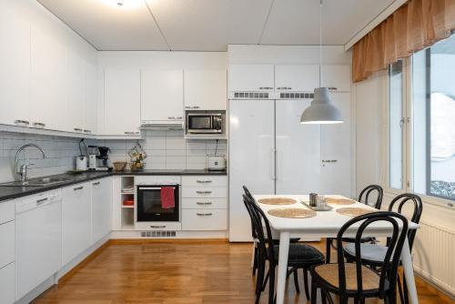 una cocina con armarios blancos y una mesa con sillas. en Kokonainen huoneisto 73m2 keskeisellä sijainnilla, ilmainen parkkipaikka, en Lahti