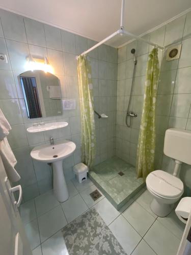 y baño con ducha, lavabo y aseo. en Pensiunea Olt Centrum Olt Centrum Panzio, en Băile Tuşnad