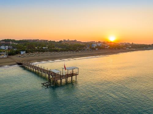a dock in the water near a beach at sunset at Asteria Family Resort Belek in Belek