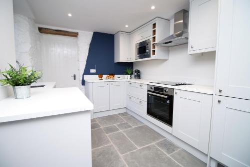 a kitchen with white cabinets and a stove at Peaceful Haven: Nature, Luxury, Wellbeing & Cuisine in Risca