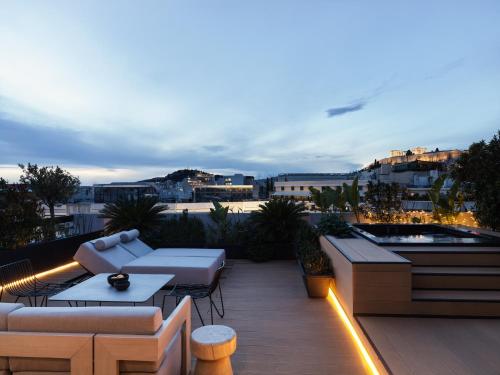 a rooftop patio with couches and tables on a building at The Newel Acropolis in Athens