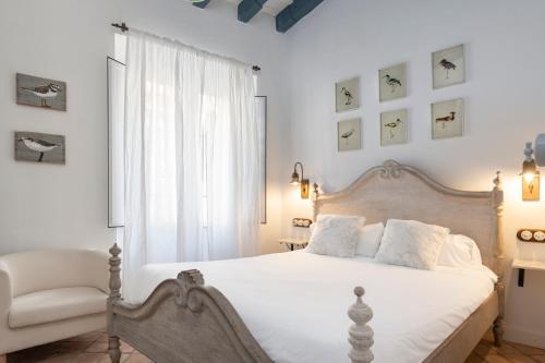 um quarto com uma cama branca e uma cadeira em Magno Apartments Vírgenes Luxury House em Sevilha
