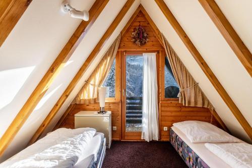 two beds in a attic room with a window at Ferienhaus Moritz in Siegsdorf