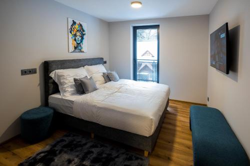 a bedroom with a bed with white sheets and a window at Apartmány Jarmilka in Bedřichov