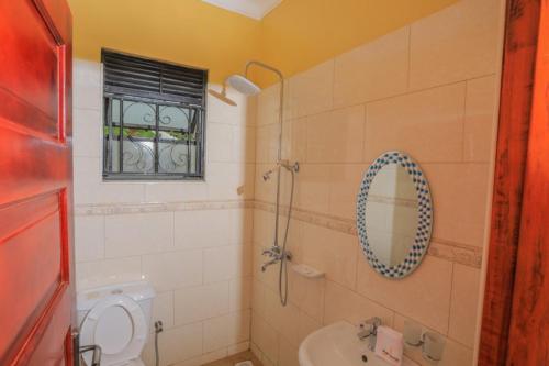 a bathroom with a shower and a toilet and a sink at Fort Suites in Fort Portal