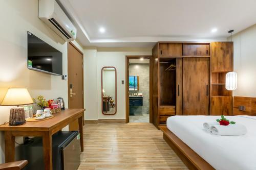 a bedroom with a large white bed and a wooden desk at Nam An Mama Villa Hoi An in Hoi An