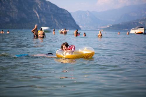 a little girl is sitting on a raft in the water at Estivo Premium Deluxe mobile homes on Camping Del Sole Village in Iseo