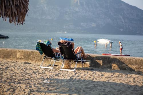 two people sitting in lawn chairs on the beach at Estivo Premium Deluxe mobile homes on Camping Del Sole Village in Iseo