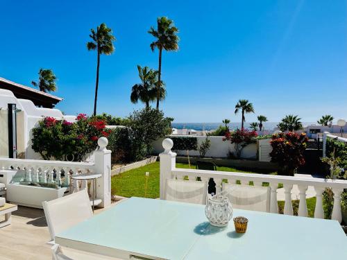 a white table and chairs on a balcony with palm trees at Villa with sea view and luxury heated pool in San Miguel de Abona