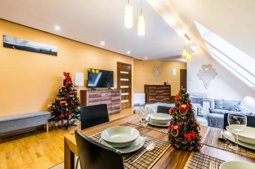 Sala de estar con mesa y árboles de Navidad en Przy Nosalu 42 Apartments SPA&SKI Jacuzzi Sauna Free, en Zakopane