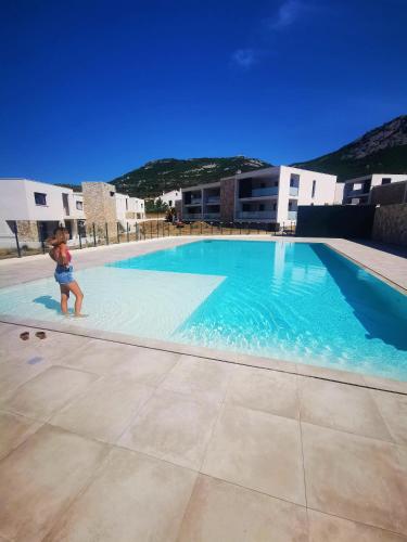une femme est debout dans une piscine dans l'établissement T3 pour 6 dans résidence neuve avec piscine, à Calvi