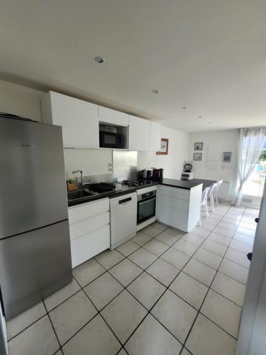 Il comprend une cuisine avec des appareils électroménagers blancs et du carrelage. dans l'établissement Sérénité Marine : Maison en Bord de Mer à Notre Dame de Monts, à Notre-Dame-de-Monts