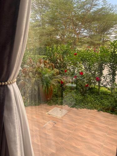 a window with a view of a garden with red roses at Lake Elementaita Manor in Gilgil