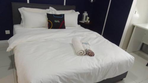 a white bed with a pair of slippers on it at Horizon Suites Ezhome in Sepang