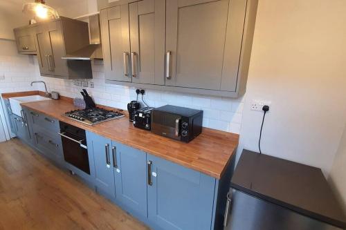 a kitchen with a counter top with a microwave at Contractors-City Centre-Parking-Sleeps 9 -Smart TV, 2 Toilets! in Coventry
