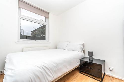 a white bedroom with a bed and a window at Bright Guest House in Hackney in London