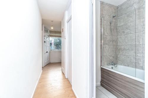 a bathroom with a tub and a walk in shower at Bright Guest House in Hackney in London