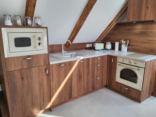 cocina con armarios de madera, fregadero y microondas en Apartmán v Podkroví, en Kremnica